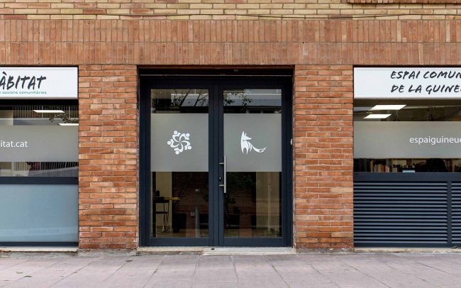 Realització de fotografies de l’Espai Comunitari de la Guineueta per a la seva web i per al disseny de tríptics i postals informatives.. Espai des del carrer, porta d'entrada i aparadors.